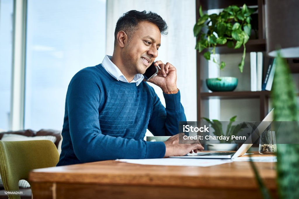 Self management is a freelancer’s greatest tool Shot of a businessman using a laptop and smartphone while working from home Using Phone Stock Photo