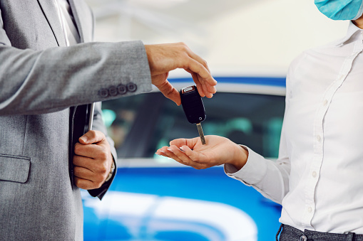 Close up of car seller handing car keys to a customer.