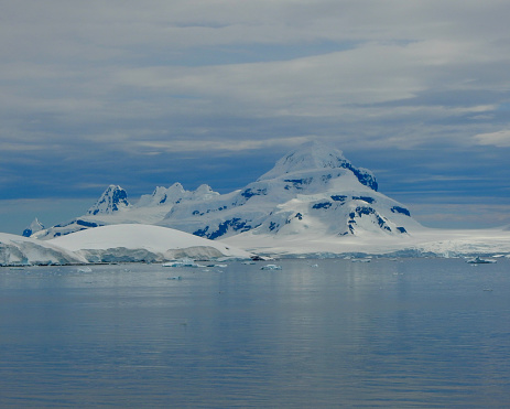 A wide shot of Base Brown (Argentina) in Antarctica set amongst cliffs, water and ice in a bleak landscape