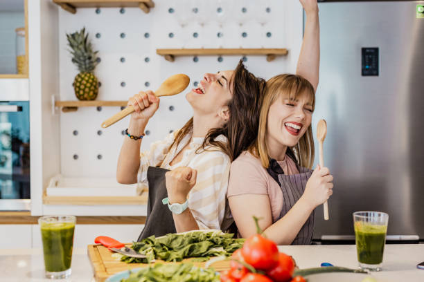 deux jeunes amis féminins cuisinant dans la cuisine - cooking chef domestic kitchen food photos et images de collection