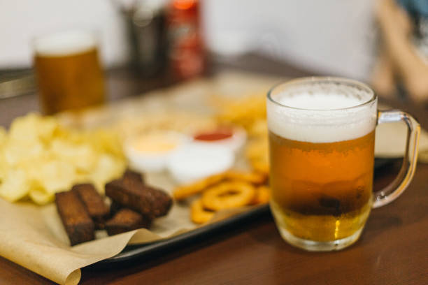 istock Lager beer and snacks on wooden table. Nuts, chips, peanut, toast, crackers. Appetizer fast food. Craft beer. Beerboard. Tomato, cheese, garlic sauce. 1294454253