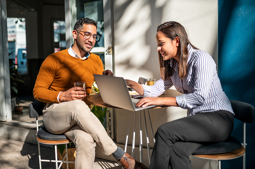 Two young people sitting at cafe and preparing presentation for meeting