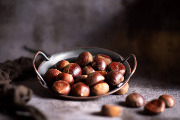 Chestnuts on a artistic metal plate in a rustic dark setup stock photo
