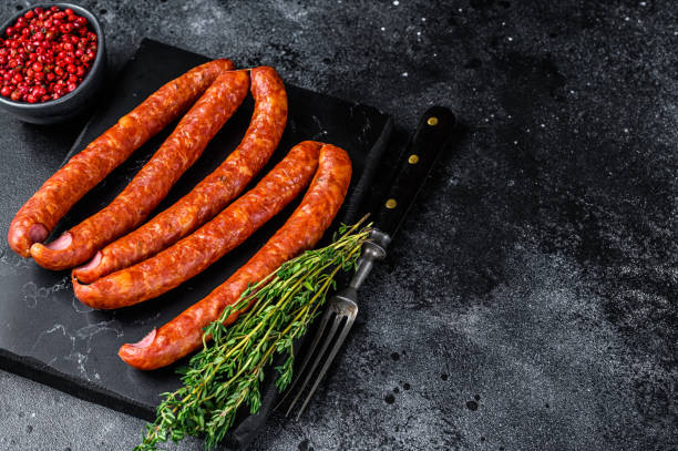 istock Smoked sausages on a marble board. Black background. Top view. Copy space 1294456922