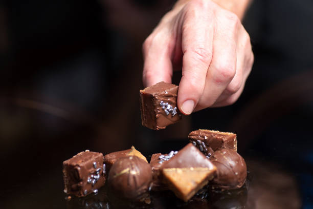 рука принимая домашний шоколад praline конфеты десерты - people snack almond brown стоковые фото и изображения