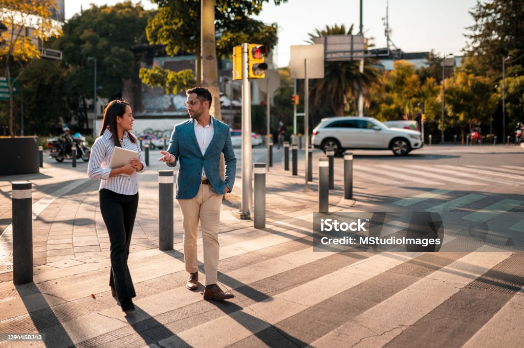 Two coworkers crossing street Two young people crossing the street Crosswalk Stock Photo