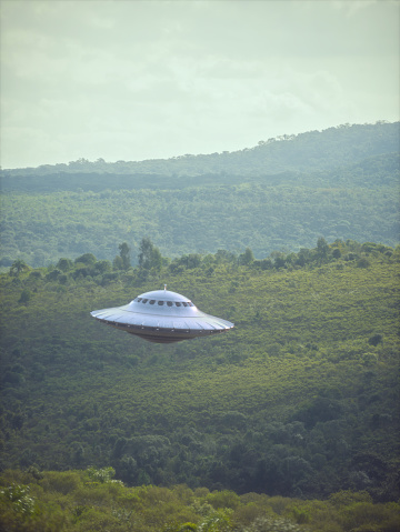 UFO, unidentified flying object, gravitating over the forest and mountain ranges.