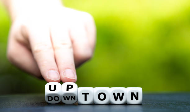 istock Hand turns dice and changes the word downtown to uptown. 1294461694
