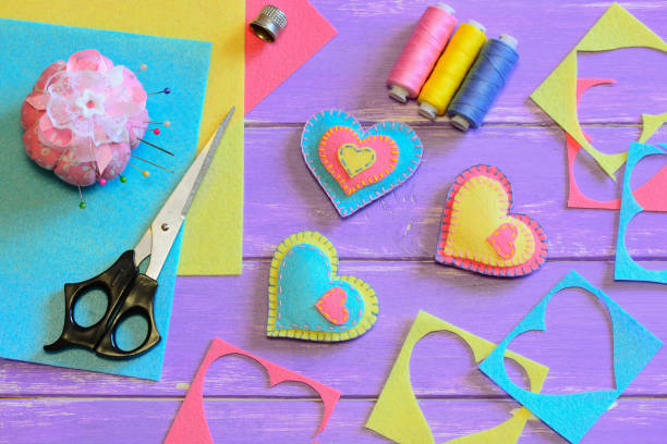istock Valentines day decorations crafts diy. Felt heart decorations, scissors, thread, pincushion, thimble, felt sheets, pieces on a wood table. Valentines present idea. Sewing homemade Valentines day gifts 1294462688