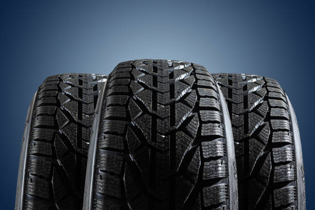 istock Stack of four new black tyres for winter car on blue background 1294462990