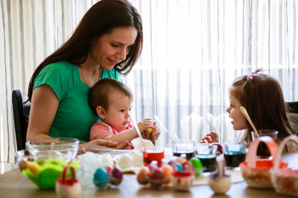 istock Toddler playing with her baby sister while dying Easter eggs with their mom 1294463806
