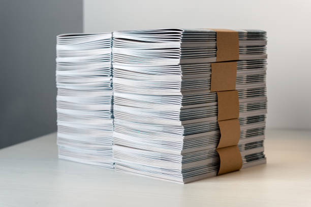 Bundles of newly printed catalogues in a stack Bundles of newly printed catalogues fastened with brown paper arranged neatly in a stack on a white table bundle photos stock pictures, royalty-free photos & images