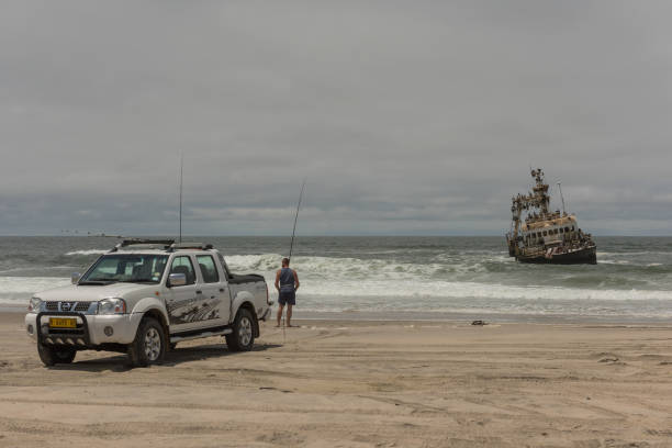 Surf fishing on the Skeleton Coast in front of the Zeila shipwreck, Namibia Surf fishing on the Skeleton Coast in front of the Zeila shipwreck, Namibia swakopmund photos stock pictures, royalty-free photos & images