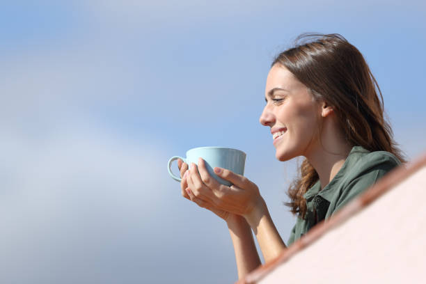 istock Happy woman contemplating from balcony drinking coffee 1294468013