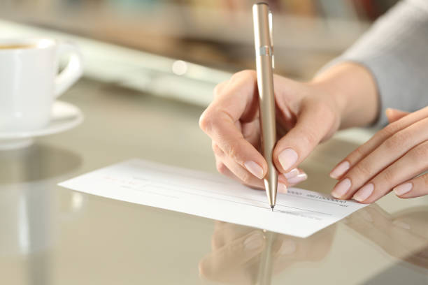 istock Woman hand writing bank check to make a payment 1294468755