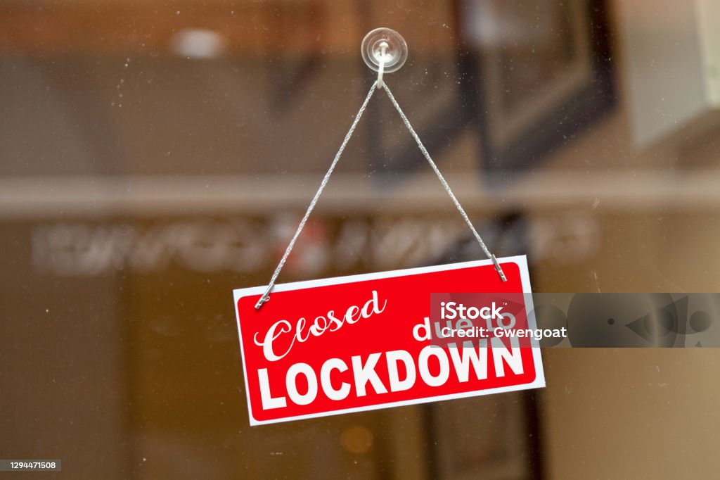 Closed due to lockdown - Closed sign Red sign hanging at the glass door of a shop with written in it "Closed due to lockdown". Building Entrance Stock Photo