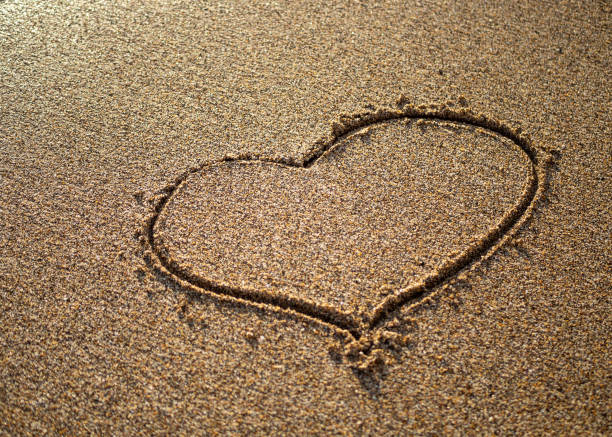 istock Heart on a sand of beach with wave on background 1294474113