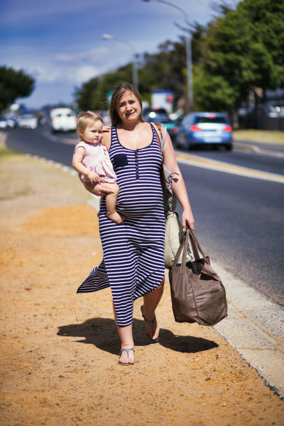 Pregnant woman carrying her baby and heavy shopping bags feels the burden of motherhood Heavily pregnant woman holds her baby. family mother poverty sadness stock pictures, royalty-free photos & images