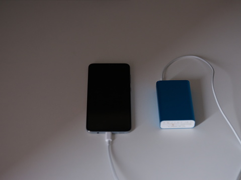 Power bank is charging the mobile phone on a white table