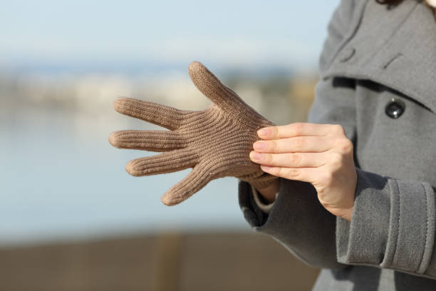 mani da donna che mettono i guanti in inverno sulla spiaggia - glove winter wool touching foto e immagini stock