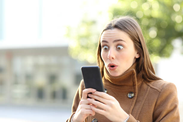 Amazed woman checking mobile phone in winter