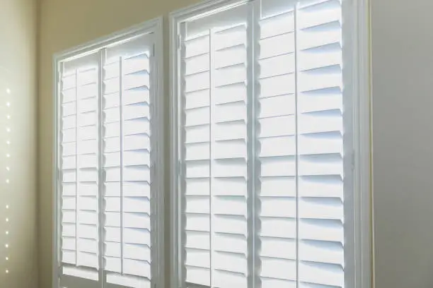 Photo of A set of open white plantation shutters in a light butter yelllow room