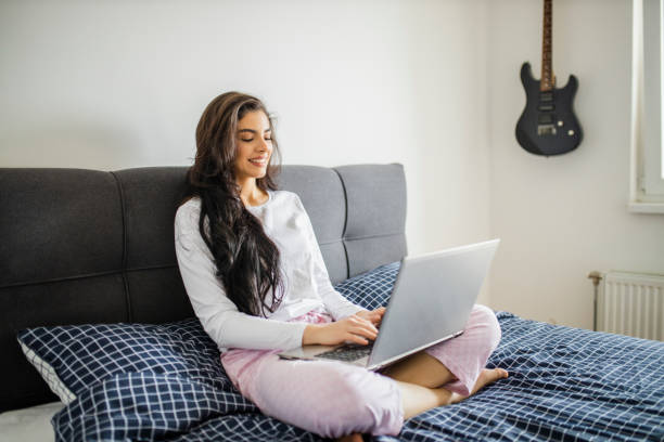 istock Young woman working from home in bed during quarantine 1294480743