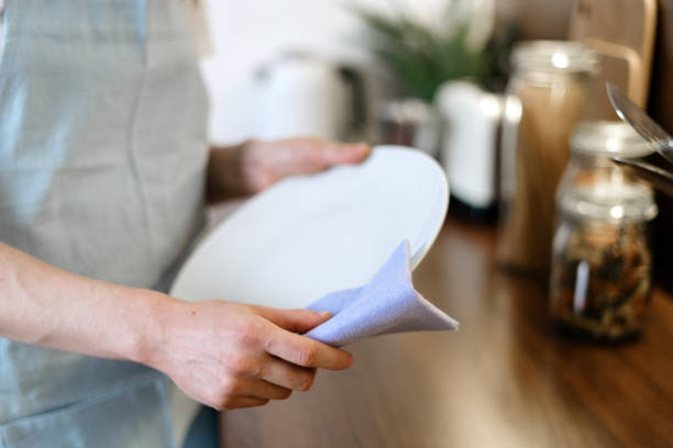 istock Woman wiping plate using towel, standing on kitchen 1294481024