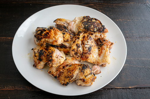 Six seared chicken thighs on a white plate