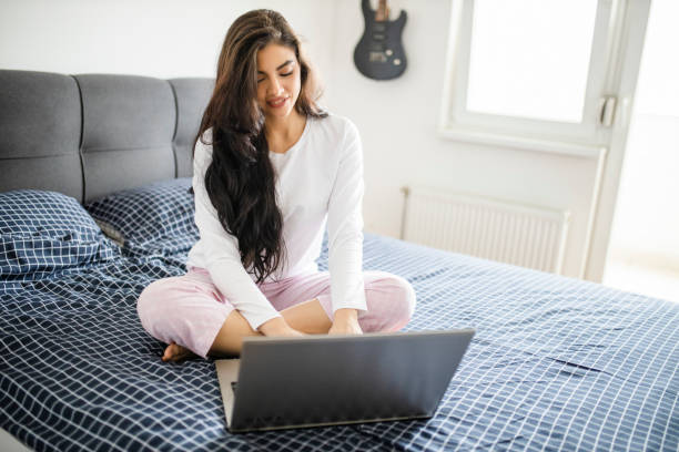 istock Young woman working from home in bed during quarantine 1294483201