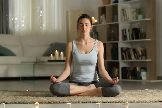 Photo of Woman doing yoga exercise in the night at home with candles