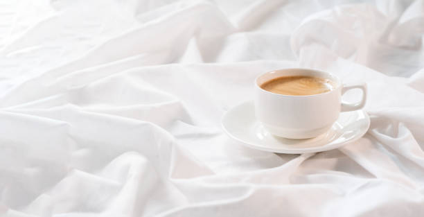 istock Cup of coffee in bed on a white sheet. Morning routine. 1294487520