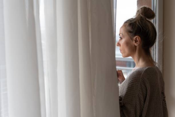istock A sad woman is looking out the window. Winter depression. 1294491141