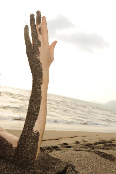 istock arm half covered in sand at the beach 1294491943