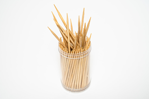 Wooden toothpicks sticking out plastic jar isolated white background. High quality photo