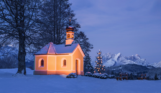 Christmas tree next to beautiful church in the mountains - moonlit night
