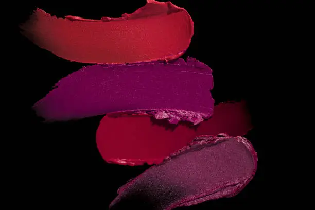 Smudged vibrant red purple scarlet pink claret maroon textured tint or lipstick on black isolated background