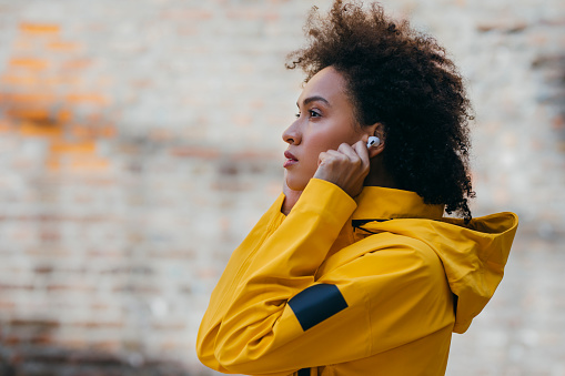 A beautiful woman wearing a yellow jacket preparing for a run in the city.
