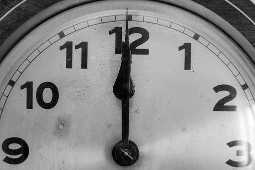 Black and white photo of an antique clock showing 12 oclock