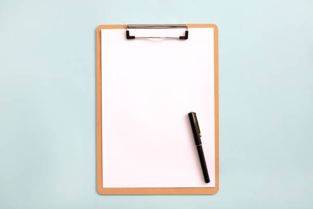 istock Overhead view of blank clipboard note pad paper with pen 1294498975