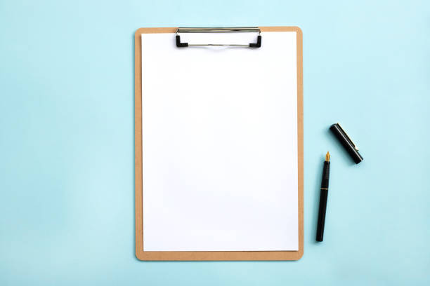 istock Overhead view of blank clipboard note pad paper with pen 1294498977