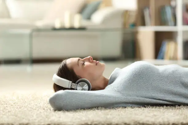 Photo of Relaxed woman listening to music with headphones at home
