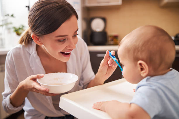 istock Positive delighted young parent feeding her baby 1294501125