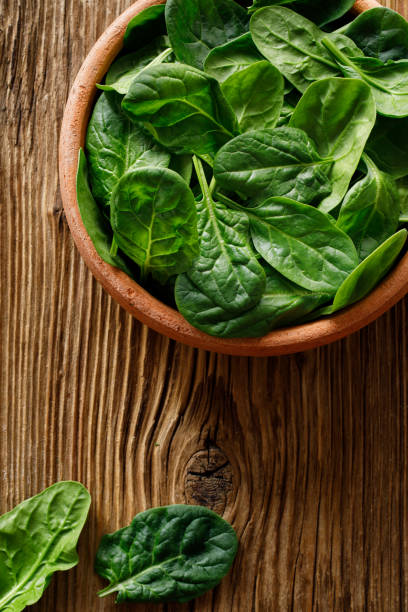istock Fresh spinach leaves in a bowl on wooden background, top view 1294509061