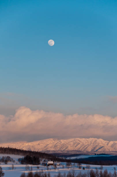 istock Rosy snowy mountain that reflects the setting sun with the moon 1294509905