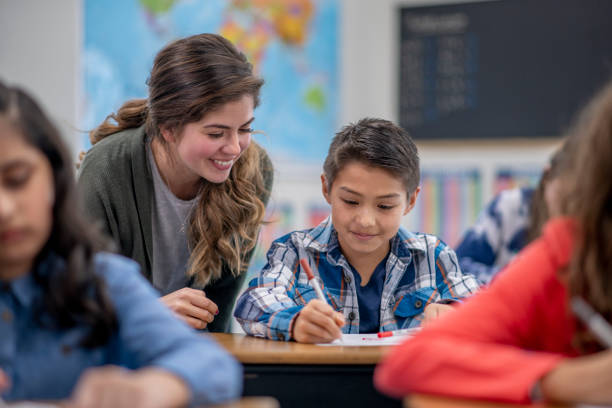 Teacher helping student in elementary classroom A Caucasian female elementary school teacher helps her student in her classroom. montessori education photos stock pictures, royalty-free photos & images