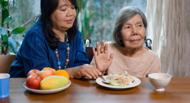 una mujer asiática mayor aburrida con comida. - musgo apretado fotografías e imágenes de stock