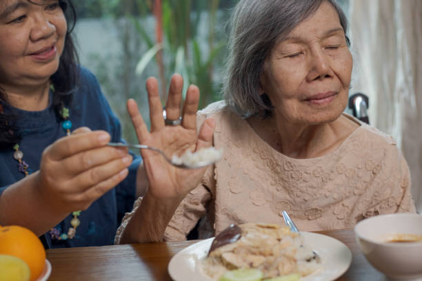 una mujer asiática mayor aburrida con comida. - musgo apretado fotografías e imágenes de stock