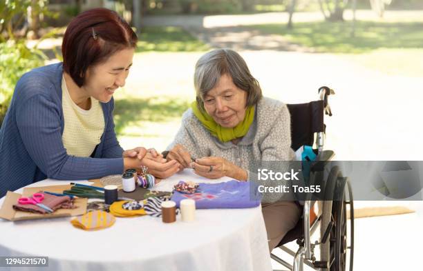 Elderly Woman And Daughter In The Needle Crafts Occupational Therapy For Alzheimers Or Dementia Stock Photo - Download Image Now