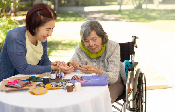 elderly woman and daughter in the needle crafts occupational therapy for alzheimer’s or dementia - japanese ethnicity women asian and indian ethnicities smiling imagens e fotografias de stock